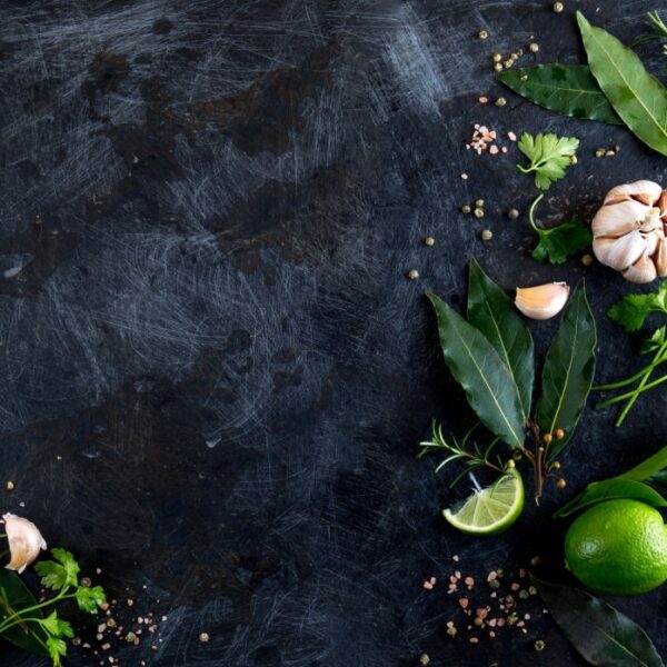 Fresh herbs and spices on black background. - garlic, laurel lime rosemary, parsley pepper.